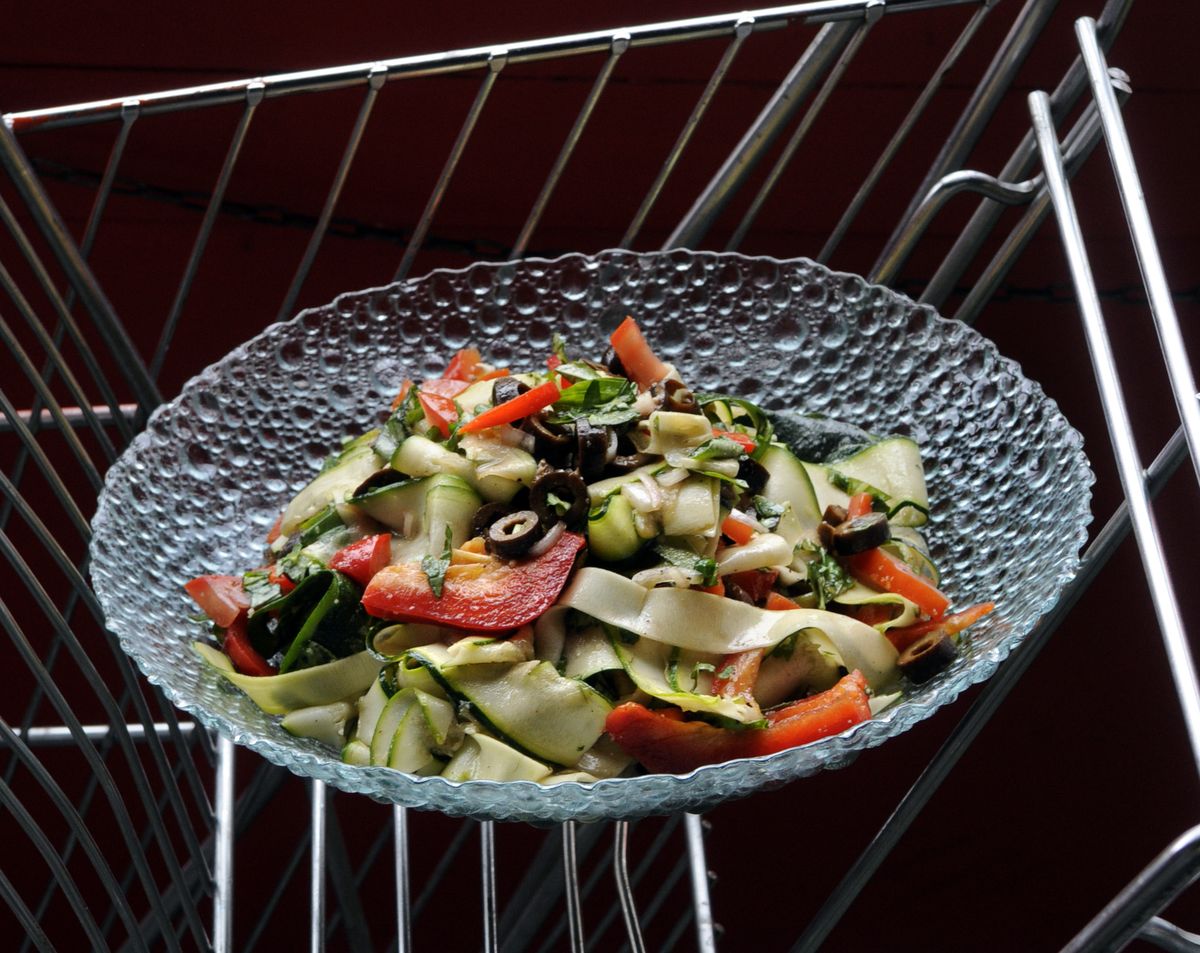 A Mediterranean salad with zucchini, basil, red peppers, olives, garlic and tomatoes.