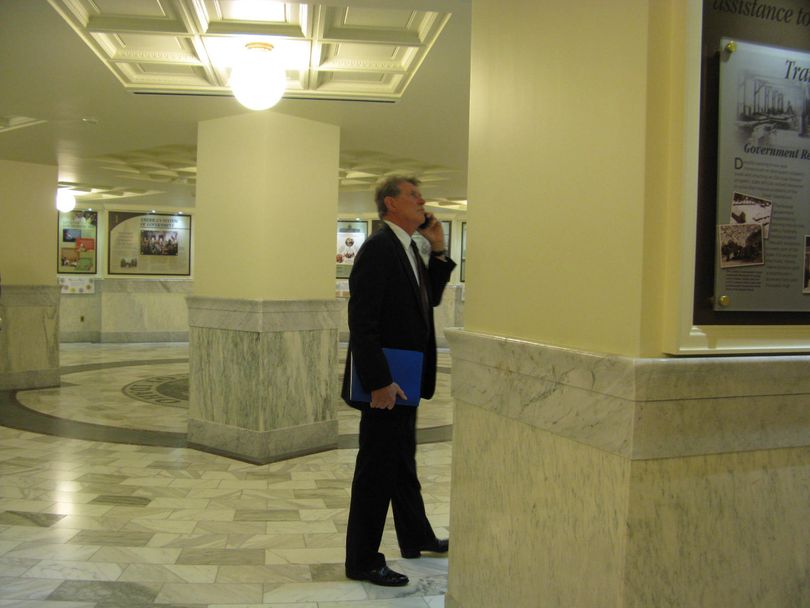 Gov. Butch Otter talks on his cell phone in the ground-floor rotunda of the Statehouse, as he waits for gay rights protesters blocking his office to be arrested and removed on Tuesday morning. (Betsy Russell)