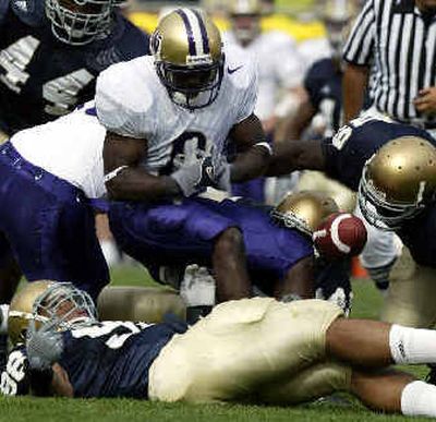 
UW's Kenny James fumbles as he is hit by Notre Dame's Brandon Hoyte, right, and Trevor Laws, bottom, during the first quarter. 
 (Associated Press / The Spokesman-Review)