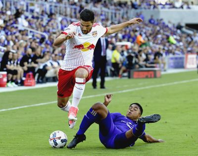 New York Red Bulls's Salvatore Zizzo, left, leaps over a tackle attempt by Orlando City's Cristian Higuita during the first half of an MLS soccer game, Sunday, April 9, 2017, in Orlando, Fla. (John Raoux / Associated Press)