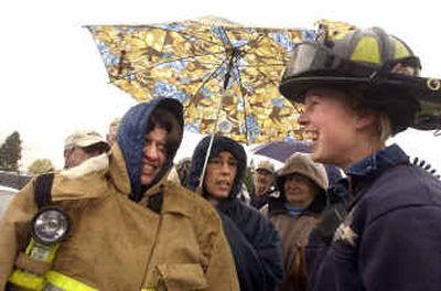 
Coeur d'Alene firefighter Mandy Jacques, right, laughs while chatting with Dawn Glasgow, who was wearing Jacques' jacket to stay warm, and Vivian Kelly, holding umbrella, while the women were part of a long line for flu shots Friday morning at Panhandle Health District in Coeur d'Alene. 
 (Jesse Tinsley / The Spokesman-Review)