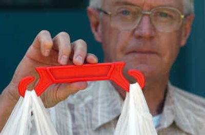 
Mel Knutson of Post Falls holds up his solution to carrying  multiple plastic shopping bags.  He calls it the Handi Hook. 
 (Jesse Tinsley / The Spokesman-Review)