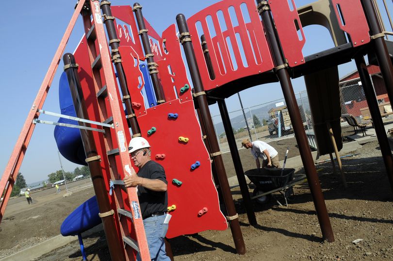 Glen Prosser of Prosser and Sons, and his son, Jason, finish up the construction of a structure playground in the new Greenacres Park at Boone Avenue and Long Road on Monday. (J. Bart Rayniak)