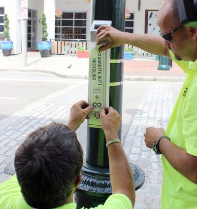 Dale Alvin, right, and Jerry Howell apply a label Monday to the first of about 50 cigarette butt recycling receptacles being installed in parts of New Orleans. (Associated Press)