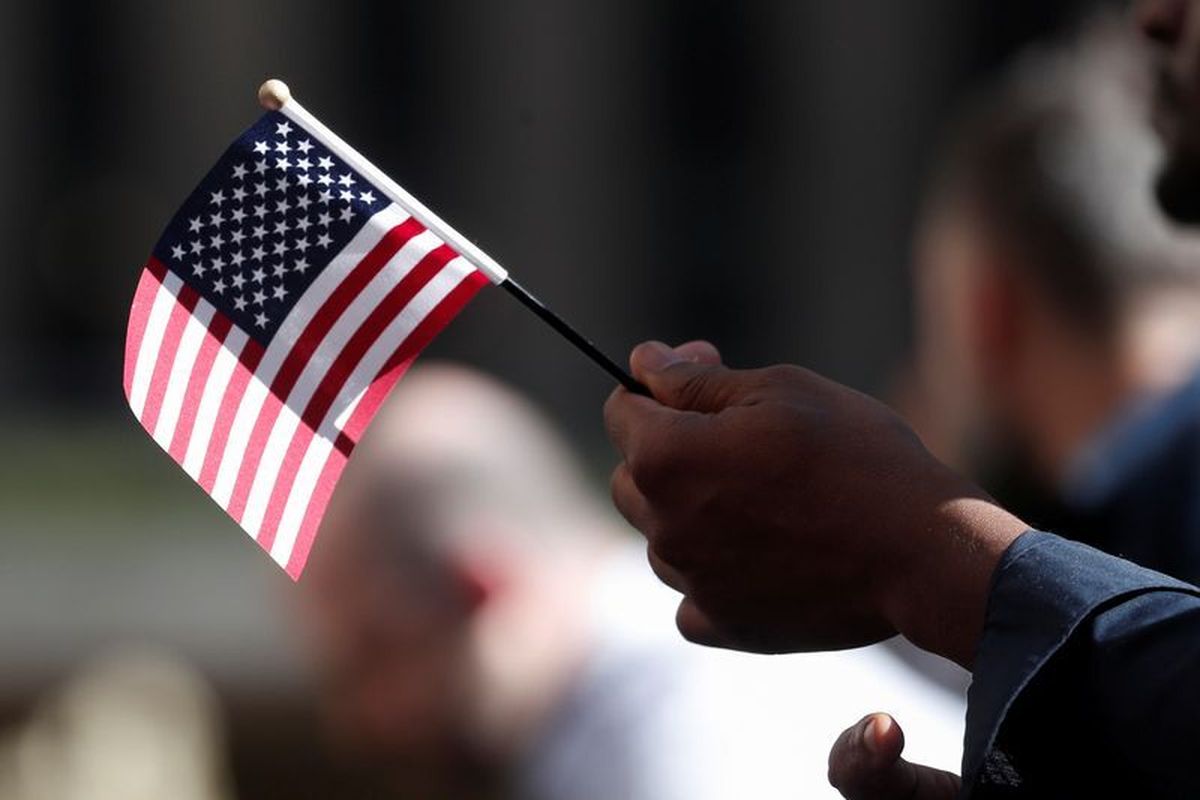 FILE PHOTO: A citizenship candidate holds a flag during the U.S. Citizenship and Immigration Services (USCIS) naturalization ceremony at Rockefeller Plaza in New York City, U.S., September 17, 2019. REUTERS/Shannon Stapleton/File Photo (SHANNON STAPLETON)