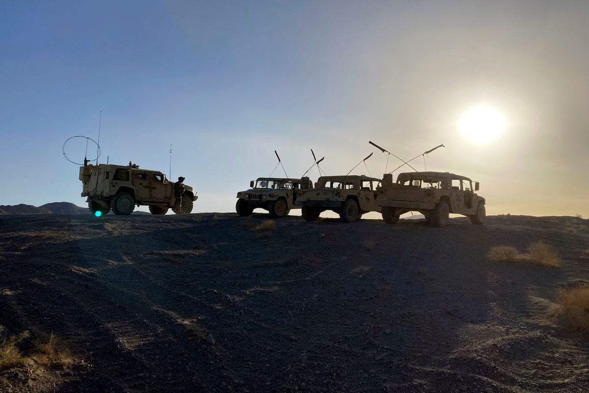 Army vehicles on the ridge, as soldiers from the 2nd Brigade, 1st Cavalry Division, prepare to attack the enemy in the town nearby, during an early morning training exercise at the National Training Center at Fort Irwin, Calif., April 12, 2022.  (Lolita C. Baldor)