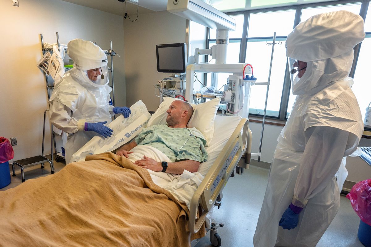 In the special pathogens unit at Providence Sacred Heart Medical Center, Darrell Ruby, plays an Ebola patient. He talks with registered nurses Marnae Ferrin, left, and Sarah Emerson during a training demonstration. The unit was one of the first places in the country that cared for people with COVID-19 in 2020. (COLIN MULVANY/The Spokesman-Review)