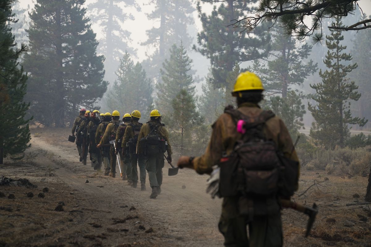 A hotshot crew from Tahoe Hotshots hikes along a trail in Meyers, Calif., Friday, Sept. 3, 2021. Fire crews took advantage of decreasing winds to battle a California wildfire near popular Lake Tahoe and were even able to allow some people back to their homes but dry weather and a weekend warming trend meant the battle was far from over.  (Jae C. Hong)