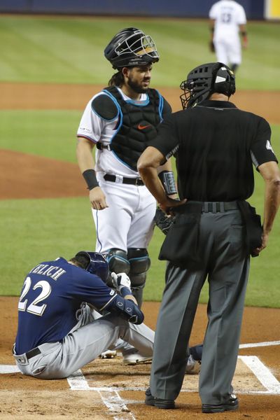 Milwaukee Brewers’ Christian Yelich (22) sits on the ground after an injury while at bat as Miami Marlins catcher Jorge Alfaro, rear, and home plate umpire Kerwin Danley look on during the first inning of a baseball game, Tuesday, Sept. 10, 2019, in Miami. (Wilfredo Lee / Associated Press)