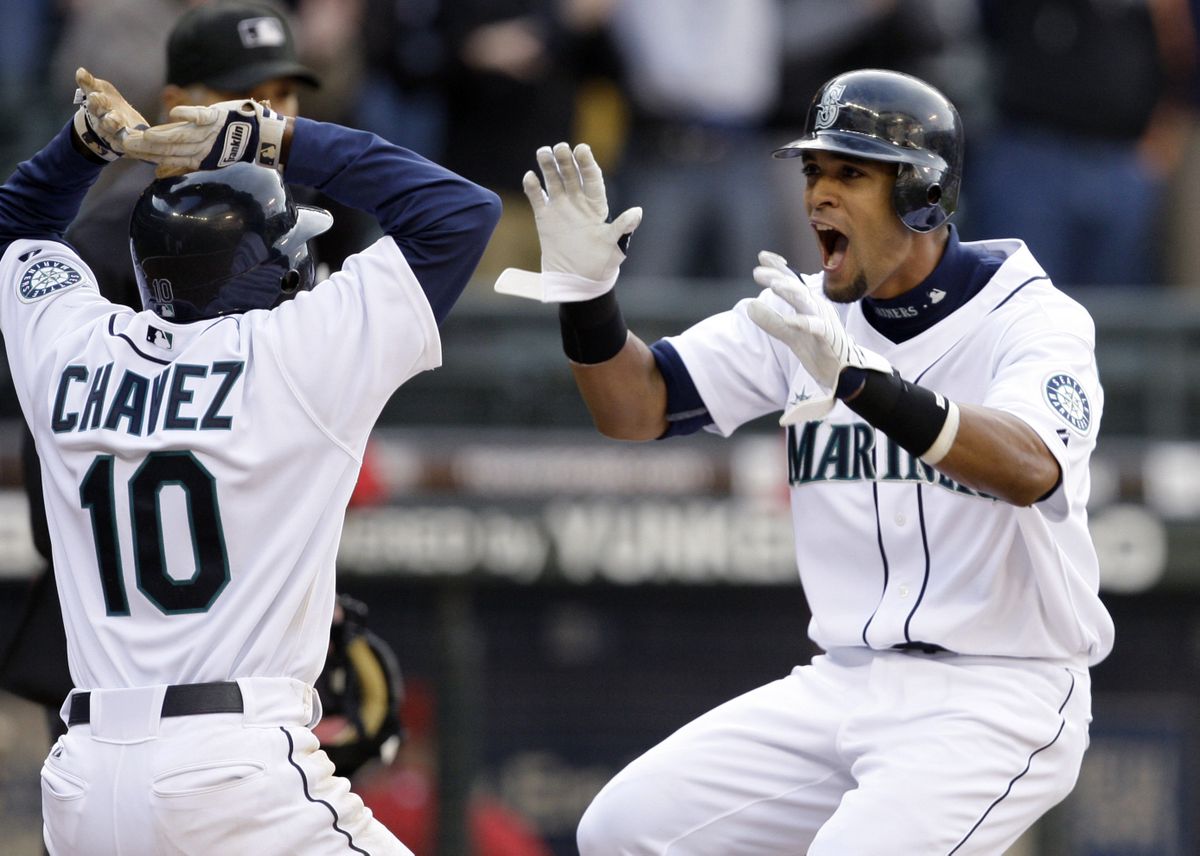 The Mariners’ Franklin Gutierrez, right, is greeted by Endy Chavez as he scores the winning run in the 10th inning. (Associated Press / The Spokesman-Review)