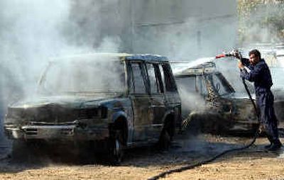An Iraqi firefighter sprays a vehicle damaged after a mortar landed on a parking lot Thursday in Baghdad. Organizations representing Iraq's Sunni minority have demanded the elections planned for Jan. 30 be delayed until security is restored.
(Associated Press / The Spokesman-Review)