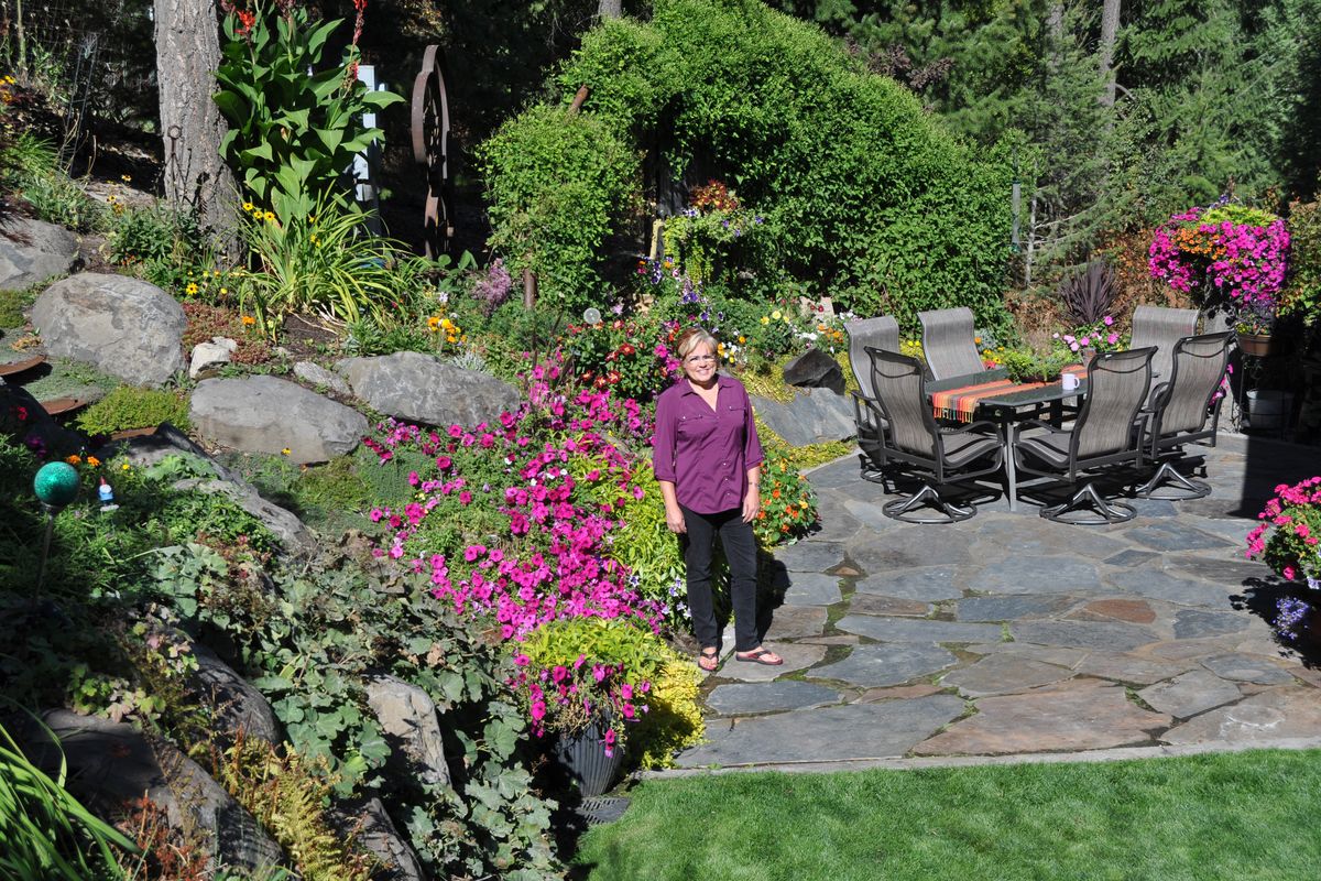 Sami Perry stands on her patio surrounded by her colorful collection of petunias and creeping Jenny. The large green vine at the back of the picture is a fall blooming clematis about ready to burst into flower. (Pat Munts)
