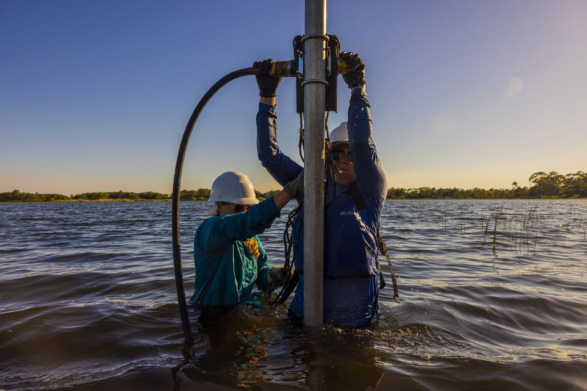Researcher Emily Elliott and her student extract a sediment core from the bottom of Campbell Lake at Topsail Hill Preserve State Park in Florida.   (Saul Martinez/for The Washington Post)