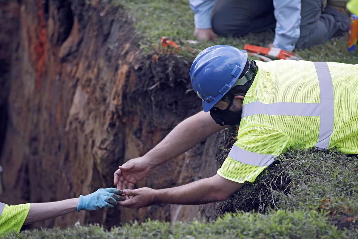 Researchers remove an item at the excavation site as work continues on an excavation of a potential unmarked mass grave from the 1921 Tulsa Race Massacre, at Oaklawn Cemetery in Tulsa, Okla., Tuesday, July 14, 2020. On May 31 and June 1 in 1921, white residents looted and burned Tulsa’s black Greenwood district, killing as many as 300 people with many believed buried in mass graves. (Mike Simons)