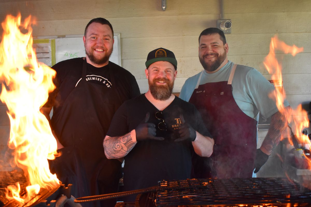 Head pitmaster Colin Barker, chef and owner Chad White and assistant pitmaster Scott Randall celebrate the second anniversary of TT’s Old Iron Brewery and BBQ in Spokane Valley on Sunday.  (Don Chareunsy/The Spokesman-Review)
