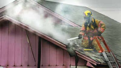 
A firefighter with Spokane County Fire District 9 puts out a hotspot in the roof of a house on North Upriver Drive early Friday. Two people died in the fire.
 (Christopher Anderson/ / The Spokesman-Review)