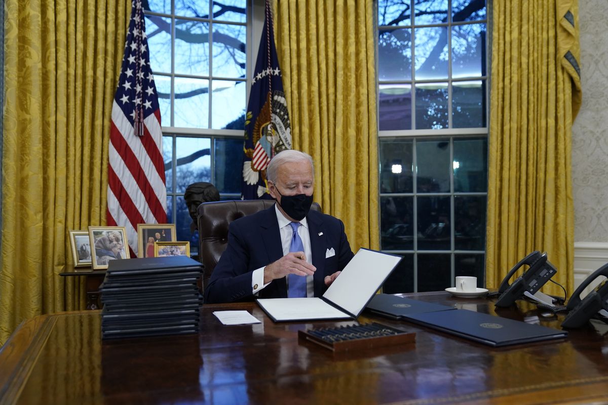 President Joe Biden signs his first executive orders in the Oval Office of the White House on Wednesday, Jan. 20, 2021, in Washington.   (Evan Vucci)