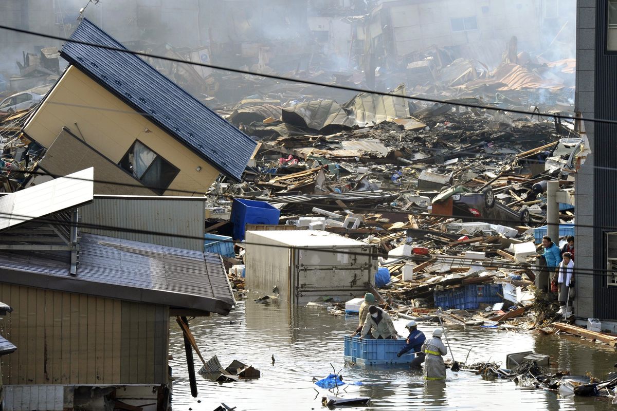 People who were left inside a building ride on a container as they are rescued in Kesennuma, northern Japan, today. (Associated Press)