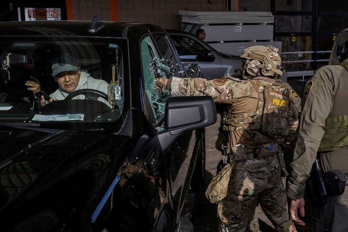 U.S. federal agents smash a car window while trying to detain a man during an immigration raid Wednesday after President Donald Trump ordered increased federal law enforcement presence to assist in crime prevention in Chicago.  (Jim Vondruska/Reuters)