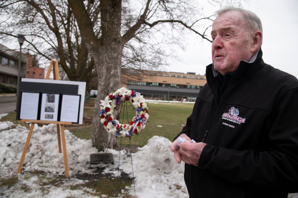 Jeff Colliton, a former Spokane City council member, stands at Gonzaga University near a plaque, wreath and informational display while talking about Paul Charvet, with whom he played college baseball at Gonzaga University as part of the class of 1962.  (Jesse Tinsley/The Spokesman-Review)