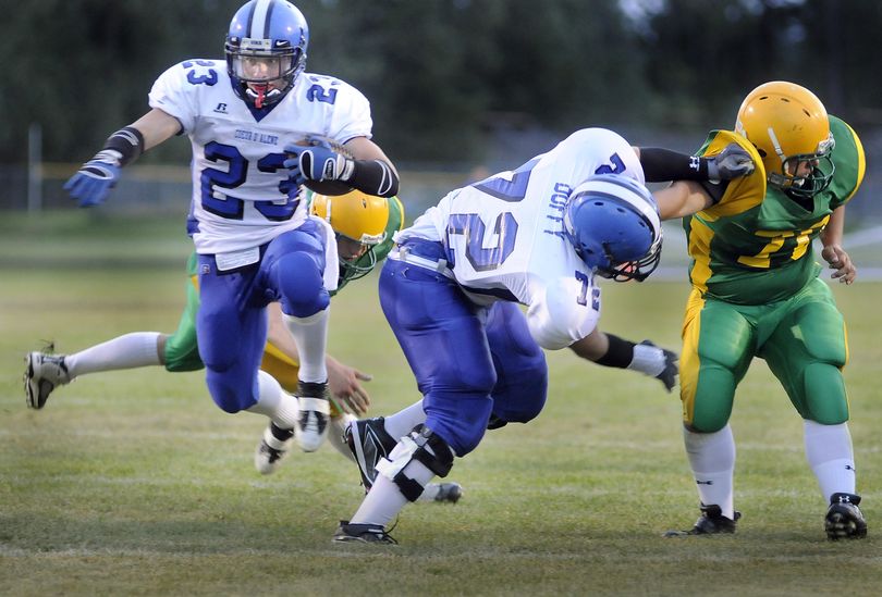 Coeur d’Alene’s Zach Keiser leaps through the line as his teammate Sean Duffy blocks early in Friday night’s season opener at Rathdrum. (CHRISTOPHER ANDERSON / The Spokesman-Review)