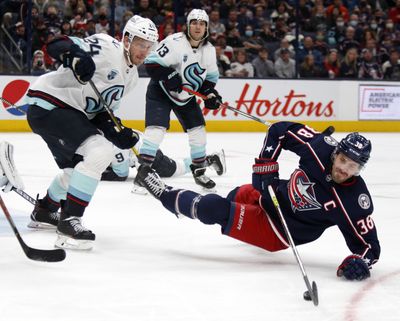 Columbus Blue Jackets forward Boone Jenner, right, reaches for the puck in front of Seattle Kraken defenseman Jamie Oleksiak, left, and forward Brandon Tanev during the second period of an NHL hockey game in Columbus, Ohio, Saturday, Oct. 16, 2021.  (Associated Press)