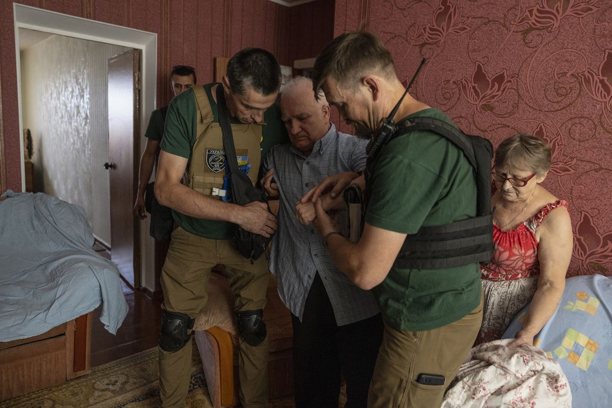 Volunteers prepare to evacuate a man named Oleksandr, largely immobile after a stroke, and his wife, Natalya, from their fourth-floor apartment in Kupyansk, Ukraine.    (Heidi Levine/For The Washington Post)