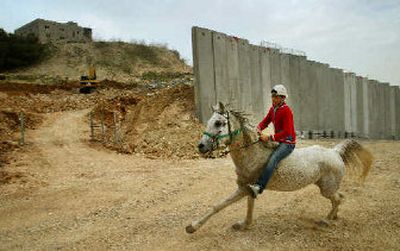 
A boy rides a horse past a break in the wall of the Israeli Security Barrier, which was still under construction, between the West Bank village of Abu Dis and Jerusalem, in this photograph taken in February. 
 (Associated Press / The Spokesman-Review)