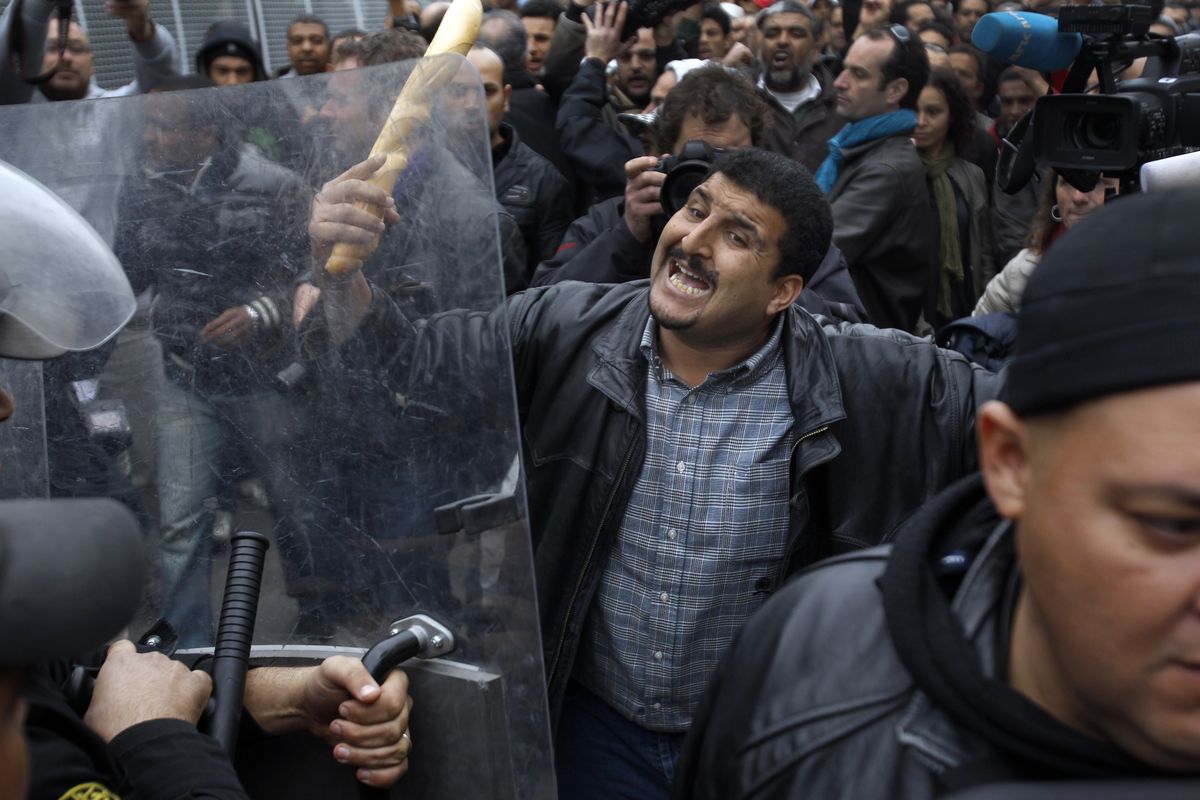 FILE - In this Jan. 18, 2011 file photo, a protestor faces riot police officers during a demonstration against the party of Tunisian ruler Ben Ali, in the center of Tunis, Tunisia. Ten years ago, an uprising in Tunisia opened the way for a wave of popular revolts against authoritarian rulers across the Middle East known as the Arab Spring. For a brief window as leaders fell, it seemed the move toward greater democracy was irreversible. Instead, the region saw its most destructive decade of the modern era.  (Christophe Ena)