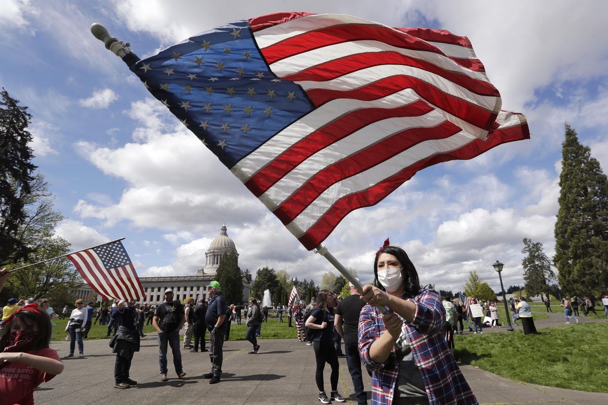 Janell Sorensen, of Woodland, Wash., waves a flag as demonstrators begin to gather at the Capitol for a protest opposing Washington state