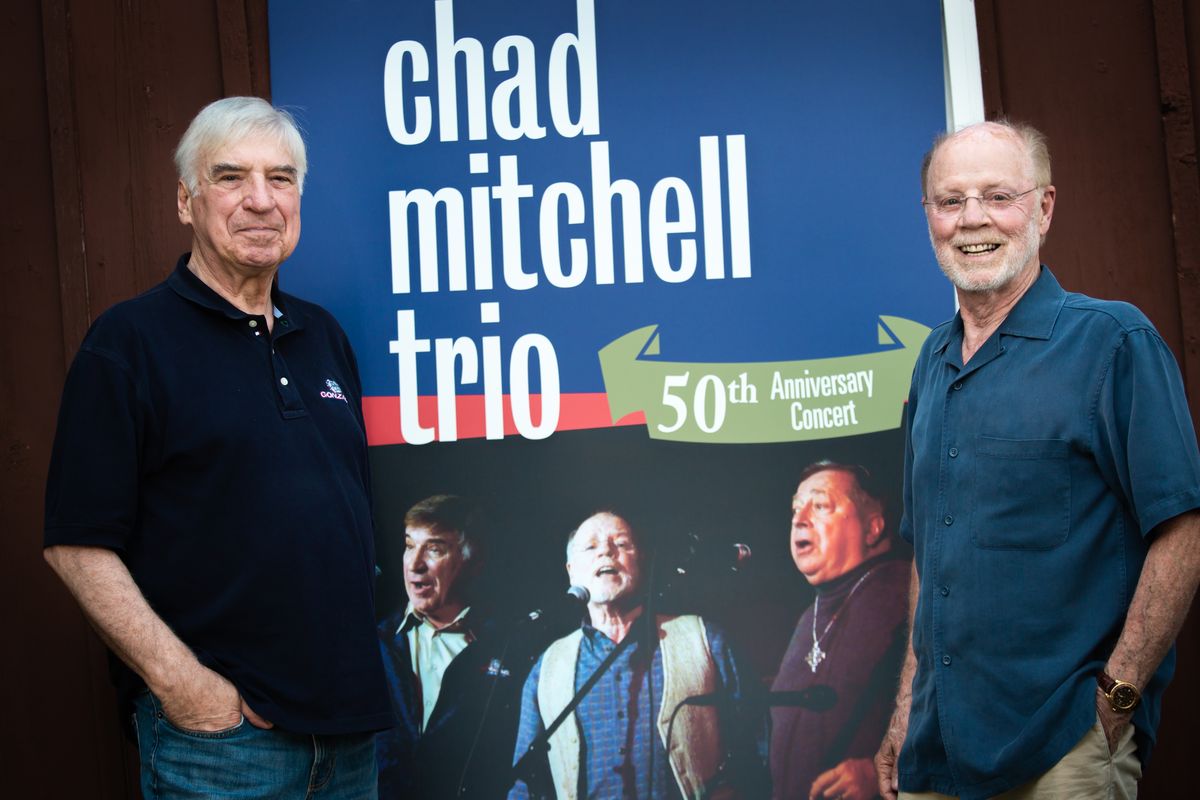 Two out of three remaining members of the Chad Mitchell Trio, who are both Spokanites and met at Gonzaga University, are Mike Kobluk, left, and Chad Mitchell, who are photographed July 12, 2021, with a large poster board from 2009 that commemorated the music group