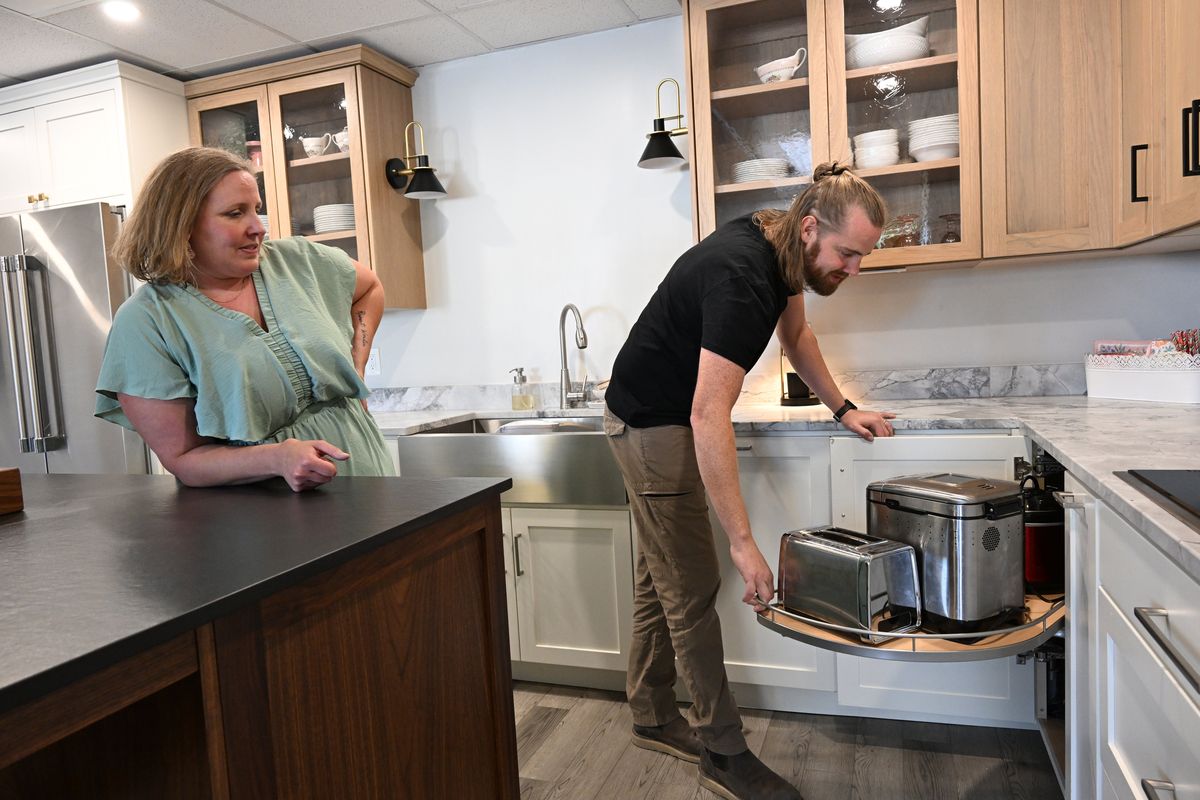Melanie DuMars watches as her brother Douglas Deniston demonstrates some of the custom cabinetry and kitchen storage ideas in the display kitchen at their family business, R&D Woodworking, in north Spokane on Aug. 8.  (Jesse Tinsley/THE SPOKESMAN-REVIEW)