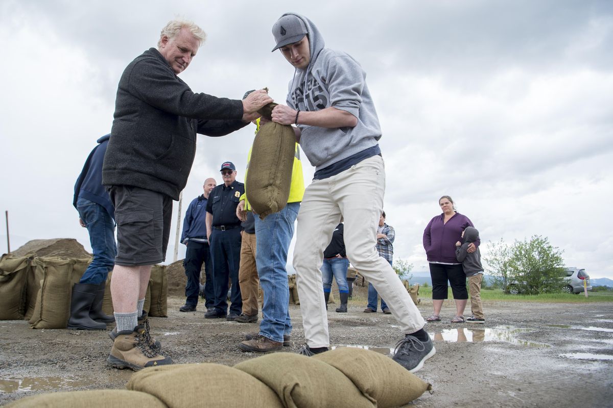 At a class to learn about sand bagging to keep flooding at bay, Joathan Hepp, left, and Ryan Revard, right, practice placing sand bags to build a dike Wednesday, May 9, 2018 at the Kalispel Tribe headquarters in Usk. (Jesse Tinsley / The Spokesman-Review)