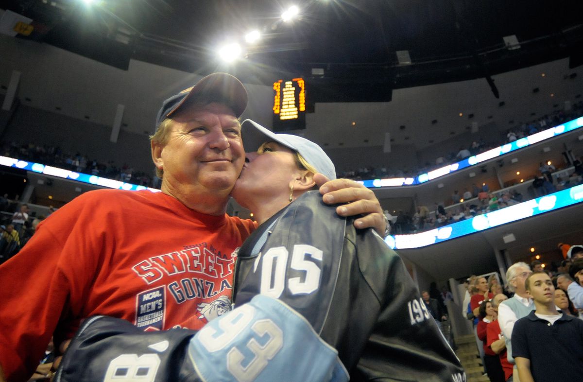 Dianne Egger leans over to kiss her husband, John, as they prepare to cheer for their separate teams at Friday’s game.  (Christopher Anderson / The Spokesman-Review)