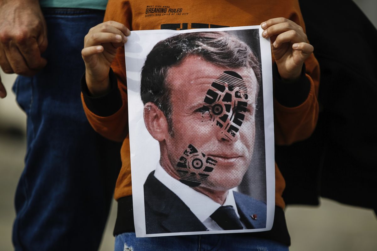 A child holds a photograph of France's President Emmanuel Macron, stamped with a shoe mark, during a protest against France in Istanbul, Sunday, Oct. 25, 2020. Turkish President Recep Tayyip Erdogan on Sunday challenged the United States to impose sanctions against his country while also launching a second attack on French President Emmanuel Macron. Speaking a day after he suggested Macron needed mental health treatment because of his attitude to Islam and Muslims, which prompted France to recall its ambassador to Ankara, Erdogan took aim at foreign critics.  (Emrah Gurel)