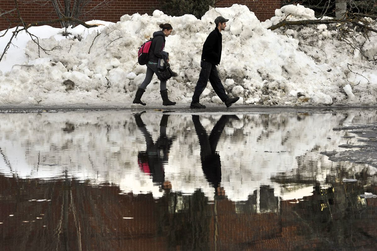 Spokane Community College education student, Kamie McCoul (cq), 20, and her boyfriend, Spokane Community College student, Shane Kelley (cq), 21, walk single file around a giant puddle in the parking lot of the SFCC campus on Jan.13, 2011.  Rising temps have cause melting snow and slush through the area. (Dan Pelle / The Spokesman-Review)