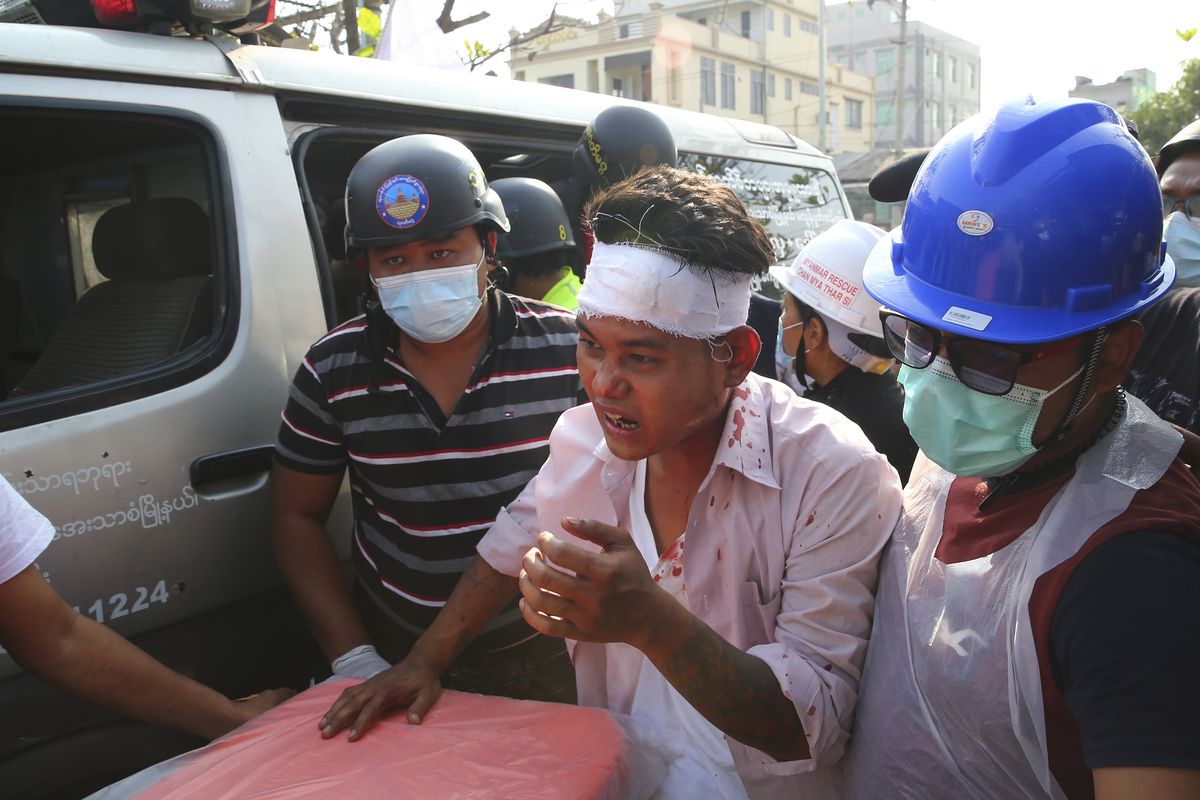 In this Feb. 26, 2021, file photo, an injured protester is escorted as police tried to disperse a demonstration against the military coup in Mandalay, Myanmar. Myanmar
