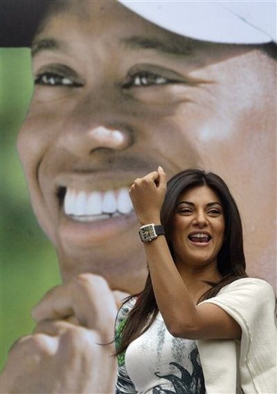 This is a March 27, 2005, file photo showing former Miss Universe and Bollywood actress Sushmita Sen posing wearing a Tag Heuer watch that the company claims to be the world's first professional golf watch designed, developed and worn by golfer Tiger Woods, on poster in background, at an event in New Delhi, India. Swiss watch maker Tag Heuer said Monday, Dec. 14, 2009, it will continue its association with Tiger Woods despite the golfer's alleged infidelities.  (Gurinder Osan / Associated Press)