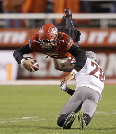 Utah quarterback Travis Wilson (7) goes airborne following a hit from WSU safety Darius Lemora. (Associated Press)