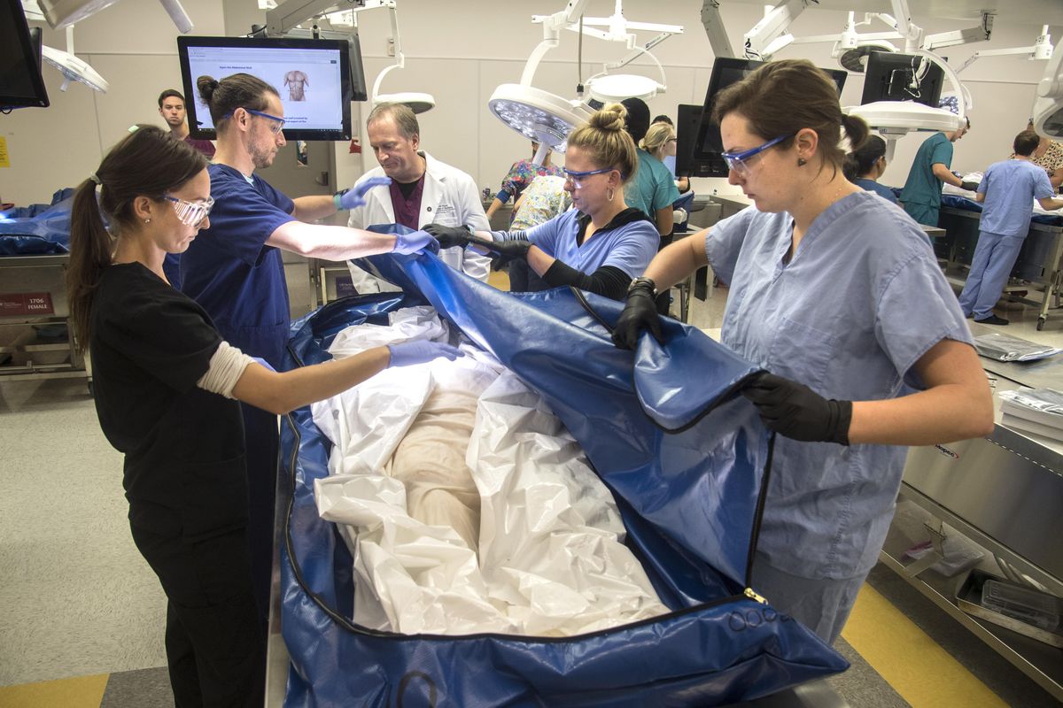WSU Medical School students, from left, Christina Street, Julian Fohrman, Chris Eglin and Hannah Winters, along with Dr. Dave Conley, center rear, open a cadaver bag containing a female at the start of their  anatomy class, Monday, Sept. 25, 2017, on the WSU Spokane campus. (Dan Pelle / The Spokesman-Review)