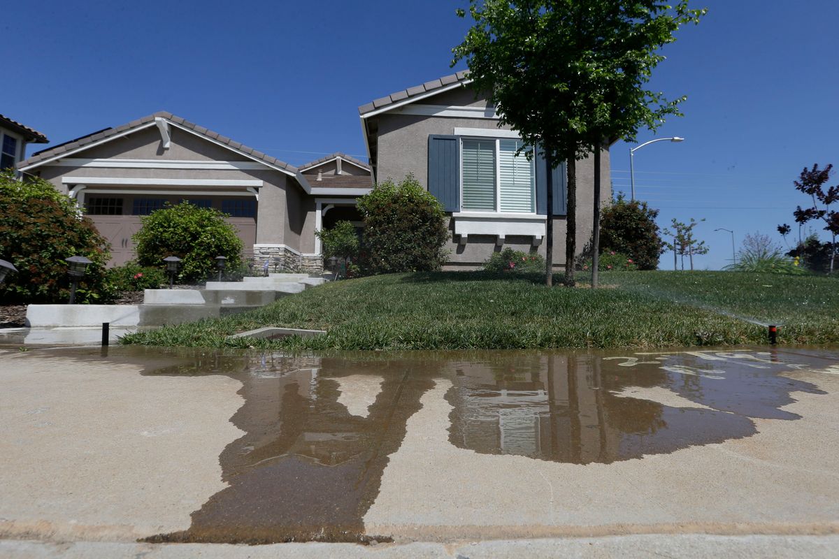 FILE — Water flows down a sidewalk from water sprinklers running at a home Thursday, April 2, 2015, in Rancho Cordova, Calif. The State Water Resources Control Board voted Tuesday, Jan. 4, 2022 to adopt mandatory water use restrictions that prohibit excessive runoff from sprinklers.  (Rich Pedroncelli)