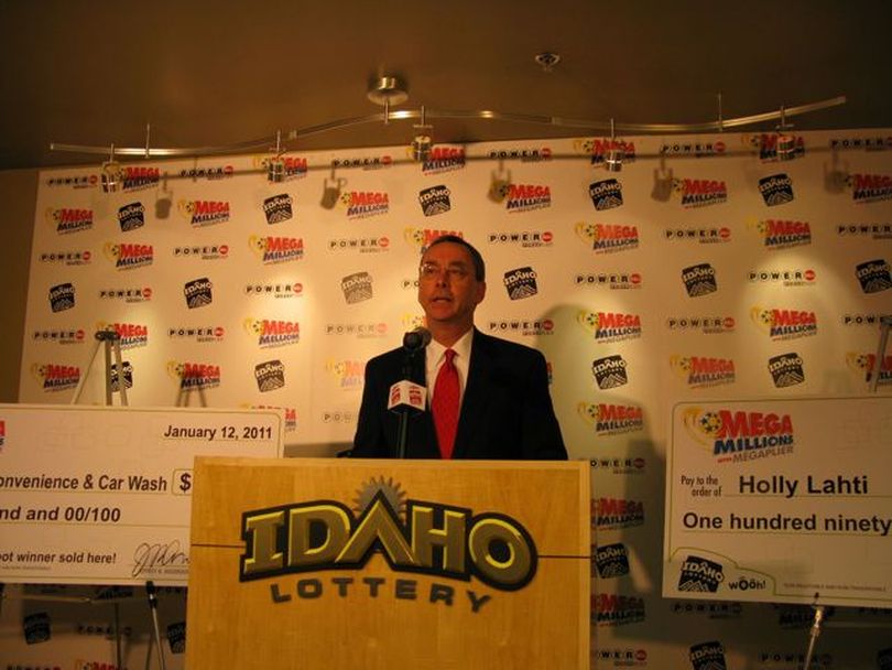 Idaho Lottery Director Jeff Anderson announces the Mega Millions winner from North Idaho. At left is a check for $50,000 to the Post Falls convenience store where the ticket was sold; at right is a mockup of a check to winner Holly Lahti for $190 million. (Betsy Russell)