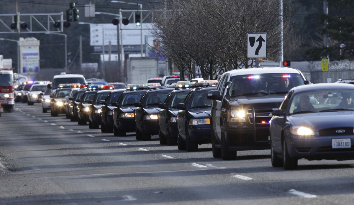 A long line of police cars follows in procession as the bodies of four slain Lakewood Police officers arrive at the Mountain View Funeral Home Tuesday, Dec. 1, 2009, in Lakewood, Wash. The four Lakewood Police officers were killed Sunday, Nov. 29, 2009 as they sat in a coffee shop in Parkland, Wash. (Ted Warren / Associated Press)