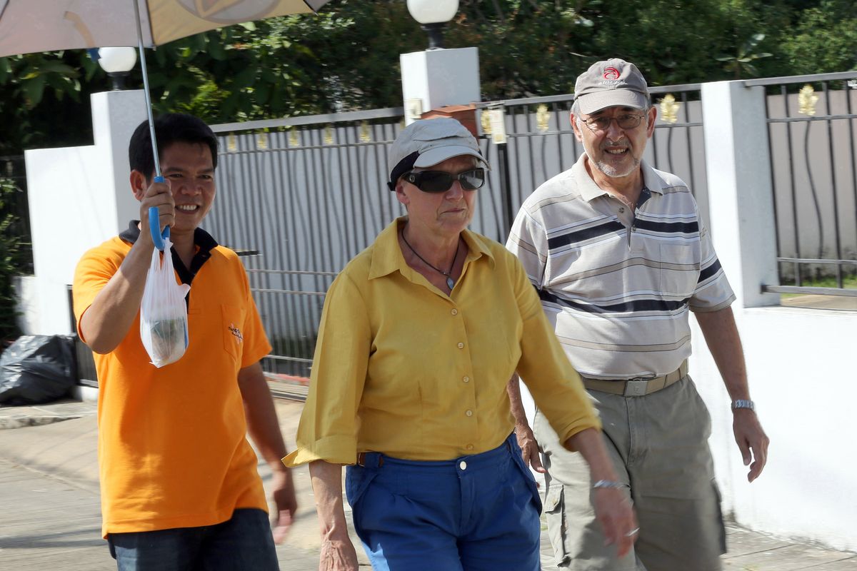 Ulrich Kuratli, right, talks with his wife, Susanna, center, an Alzheimer’s patient from Switzerland, as she is escorted by a Thai caretaker on November 13. (Associated Press)
