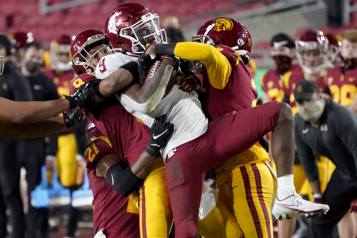 Southern California cornerback Chris Steele, left, and cornerback Olaijah Griffin, right, bring down Washington State wide receiver Renard Bell, center, after a catch during the second half of an NCAA college football game in Los Angeles, Sunday, Dec. 6, 2020.  (Associated Press)