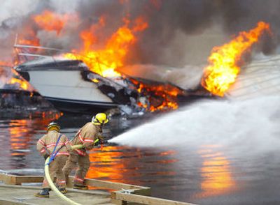 
Firefighters battle the fire at the Harborview Marina in Gig Harbor, Wash., Wednesday. Firefighters monitored the smoldering wreckage of a downtown marina Wednesday after an early morning fire burned 50 boats and spewed billowing black smoke. No injuries were reported, fire spokeswoman Penny Hulse said. One person living aboard a boat fled the covered marina before it was charred, she said. 
 (Associated Press / The Spokesman-Review)