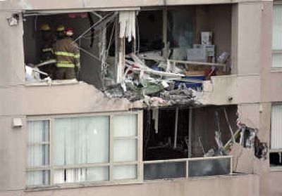 
Fire officials survey the damage to an apartment after a small plane crashed into the building in Richmond, B.C., on Friday. One person was killed and two were injured, officials said. Associated Press
 (Associated Press / The Spokesman-Review)