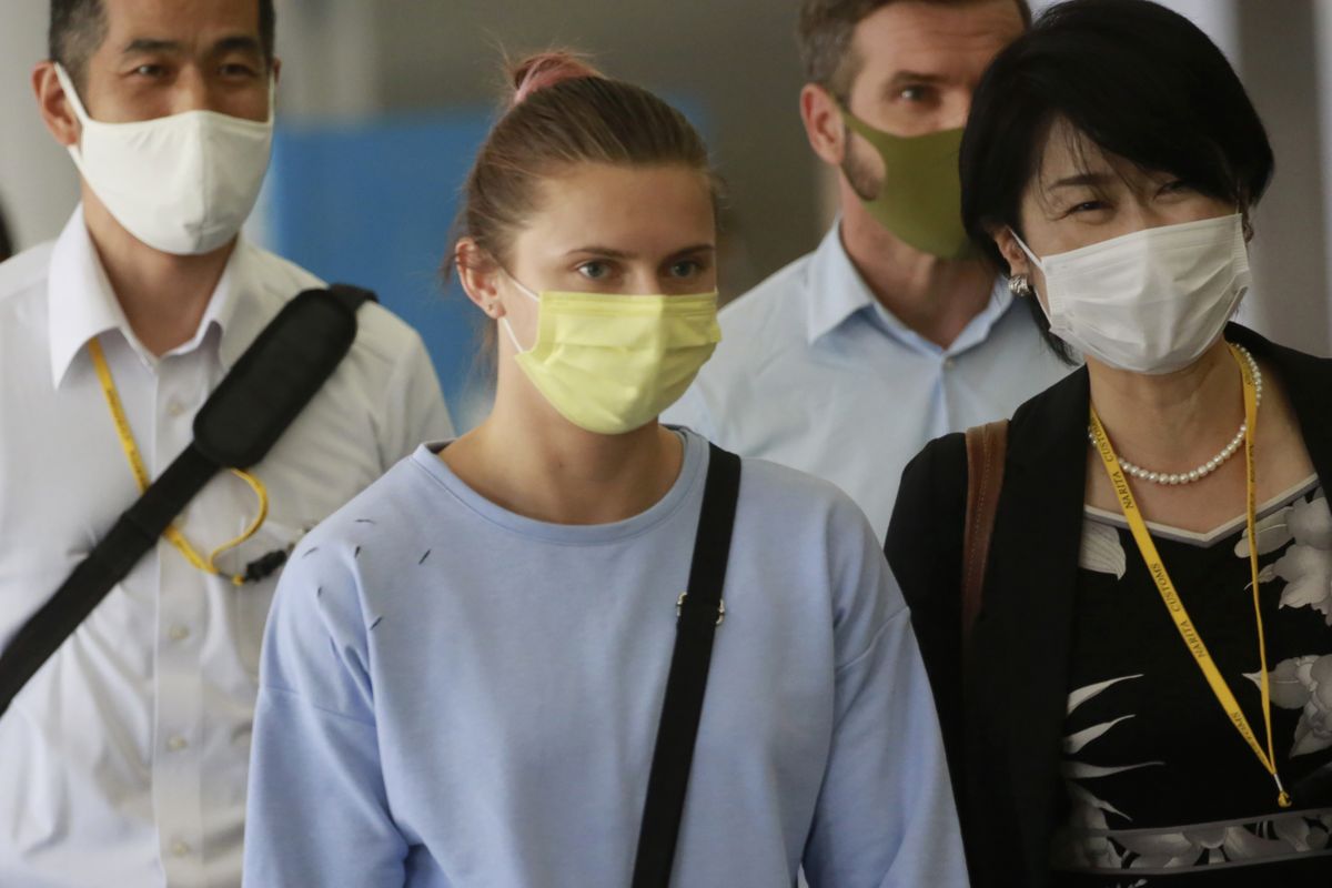 Belarusian Olympic sprinter Krystsina Tsimanouskaya, center, arrives at Narita International Airport in Narita, east of Tokyo Wednesday, Aug. 4, 2021. Tsimanouskaya plans to seek refuge in Europe after accusing team officials of trying to force her to leave the Tokyo Games early.  (Koji Sasahara)