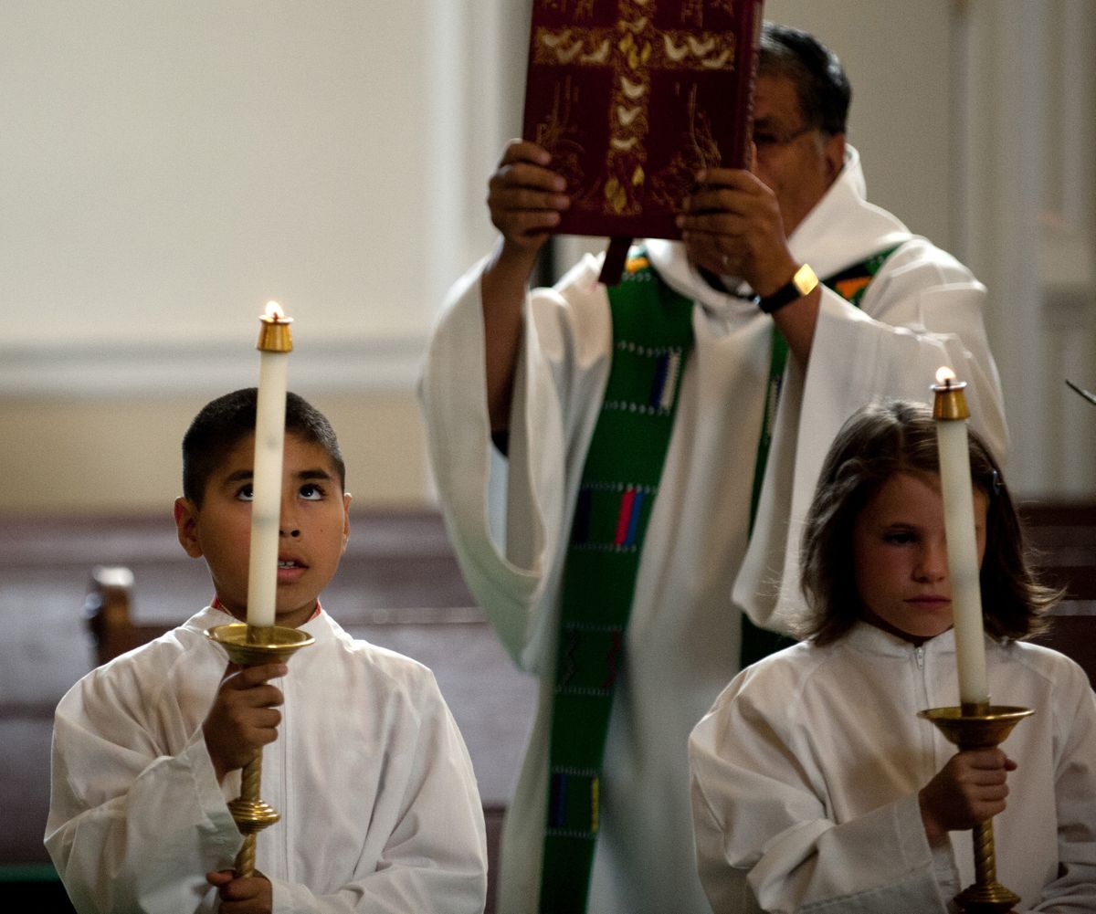 Julian Arias, left, keeps an eye on a candle as he serves as an altar boy on July 1 at St. Joseph's Church in Spokane.