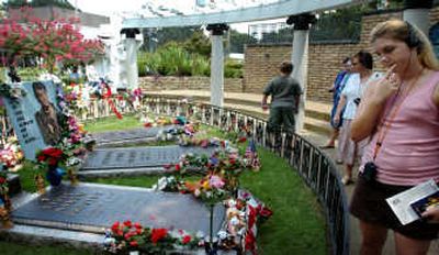 A fan walks past the grave of Elvis Presley while taking a tour at Graceland in Memphis, Tenn. The thousands of Elvis Presley fans descending on Memphis for the 30th anniversary of his death Aug. 16 won't see much sign of it, but plans are moving along for big-time changes at Graceland. Managers of Presley's famous home want to overhaul its tourist complex — with a new visitors center bigger than a football field, a convention hotel and high-tech museum displays that can give a new, digital life to the King himself. Associated Press
 (Associated Press / The Spokesman-Review)
